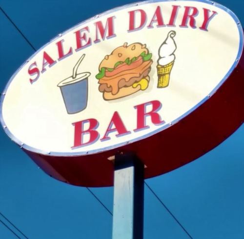 Sign for Salem Dairy Bar featuring a burger, ice cream cone, and drink, set against a blue sky.