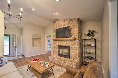 Cozy living room with a stone fireplace, TV, and modern decor, featuring a sofa and wooden coffee table.