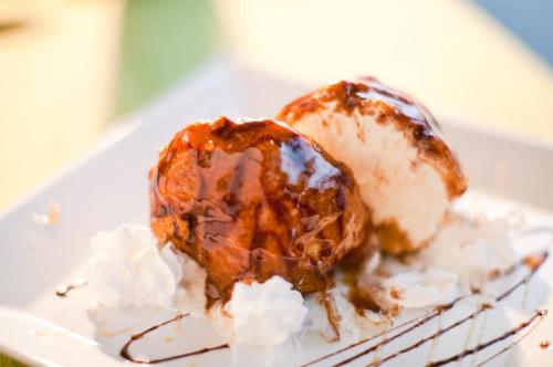 Two scoops of ice cream drizzled with chocolate sauce, served on a plate with whipped cream.