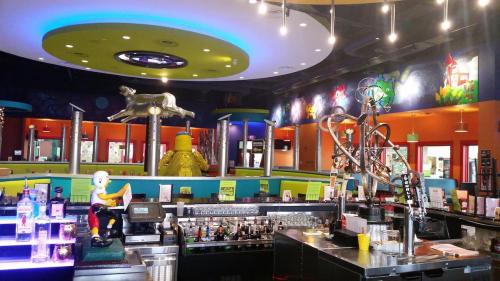 Colorful restaurant interior featuring a bar, vibrant murals, and unique decor elements like a statue and playful lighting.