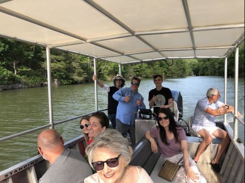 A group of people enjoying a boat ride on a lake, smiling and relaxing under a canopy.