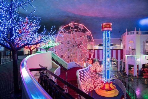 Colorful indoor amusement park with a ferris wheel, bright lights, and festive decorations.