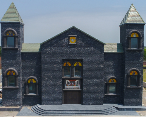 A large, dark stone church with two towers, stained glass windows, and a prominent entrance.