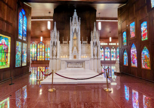 A serene chapel interior featuring a white altar, stained glass windows, and elegant decor.