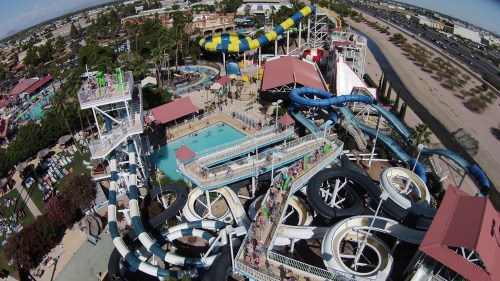 Aerial view of a vibrant water park featuring slides, pools, and visitors enjoying the attractions under a clear sky.