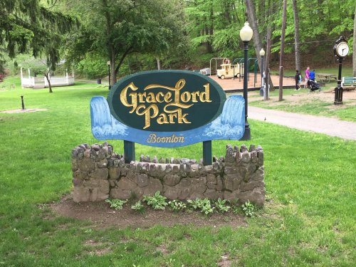 Sign for Grace Lord Park in Boonton, surrounded by greenery and stone landscaping. Playground visible in the background.