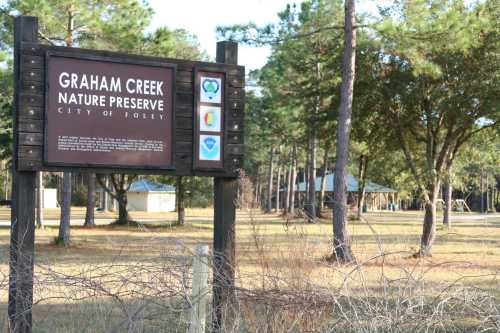 Sign for Graham Creek Nature Preserve in Foley, surrounded by trees and open grassy areas.