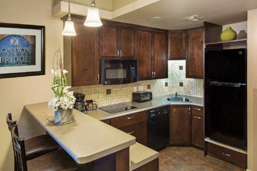 A modern kitchen with dark wood cabinets, a bar counter, and stainless steel appliances. Flowers on the counter add a touch of decor.