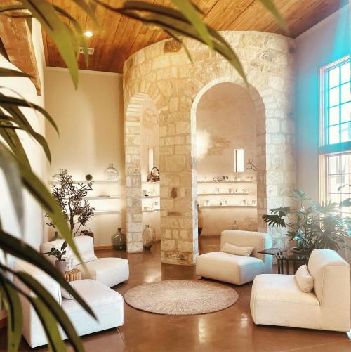 A cozy, modern interior featuring white furniture, stone walls, and plants, creating a warm, inviting atmosphere.