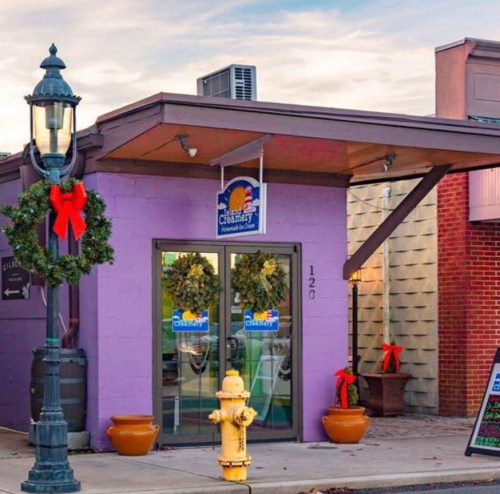 A quaint storefront with holiday decorations, featuring a sign that reads "Creamery" and a festive wreath on the door.