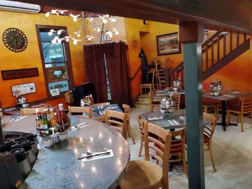Cozy restaurant interior with wooden tables, a circular bar, and warm orange walls, featuring condiments and decor.