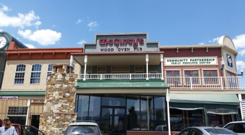 Exterior view of McGinty’s Wood Oven Pub, featuring a stone structure and nearby community resource center.
