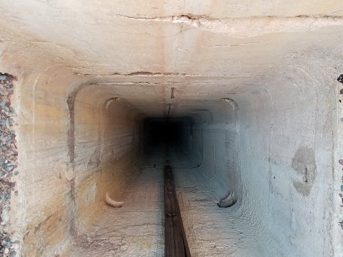 A deep, empty tunnel with smooth, light-colored walls leading into darkness.