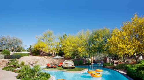 A serene pool area surrounded by vibrant yellow trees and lounge chairs under a clear blue sky.