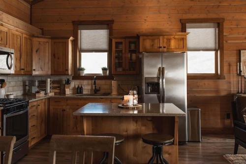 Cozy wooden kitchen with stainless steel appliances, a central island, and natural light from two windows.