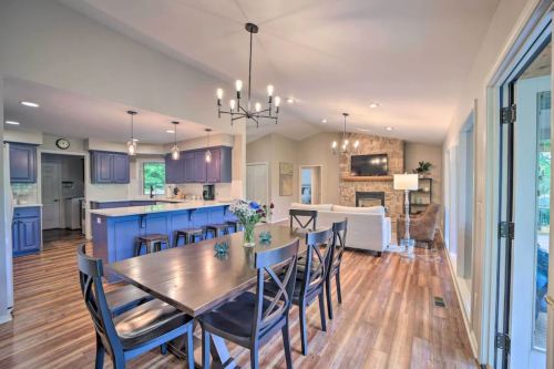 Modern open-concept kitchen and dining area with blue cabinets, wooden floors, and a cozy living room with a stone fireplace.