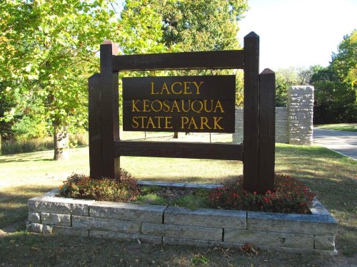Sign for Lacey Keosauqua State Park, surrounded by greenery and flowers, with a clear blue sky in the background.