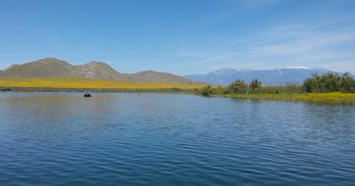 A serene lake surrounded by mountains and lush greenery under a clear blue sky.