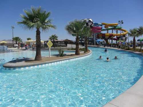 A sunny water park scene featuring a lazy river, palm trees, and colorful water slides in the background.