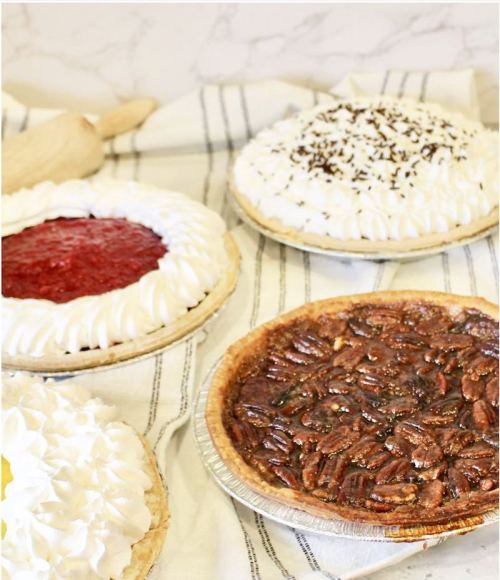 Four delicious pies on a striped cloth: strawberry, chocolate cream, coconut cream, and pecan pie.