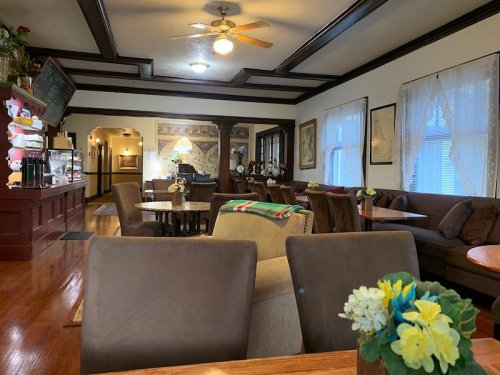 Cozy café interior with wooden accents, comfortable seating, and floral decorations on tables. Warm, inviting atmosphere.