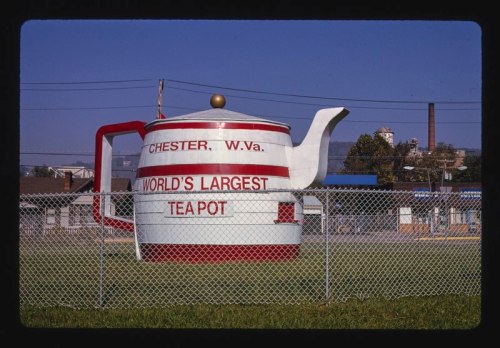 A large teapot sculpture with "World's Largest Teapot" sign, located in Chester, West Virginia, surrounded by a fence.