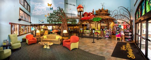 Colorful lobby of a whimsical hotel with tree-themed decor, cozy seating, and a gift shop area.