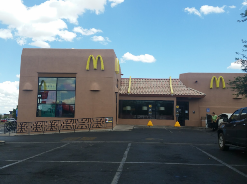 A McDonald's restaurant with a unique architectural design, featuring a blue sky and clouds in the background.