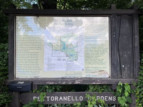 Signboard displaying a map and rules for the Mountain Lakes Open Space Area, surrounded by greenery.