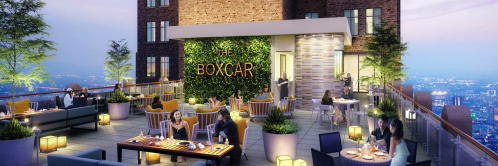 Rooftop dining area with modern furniture, greenery, and city views, featuring guests enjoying meals at The Boxcar.