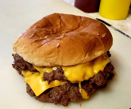 A double cheeseburger with two beef patties and melted cheddar cheese on a soft bun.