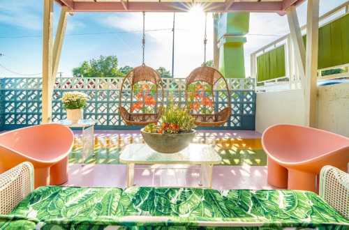 A vibrant outdoor seating area with hanging chairs, colorful decor, and a sunny backdrop.