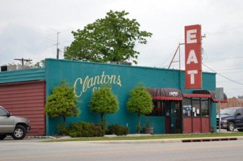 A colorful diner named Clanton's with a large "EAT" sign, surrounded by trees and parked cars.