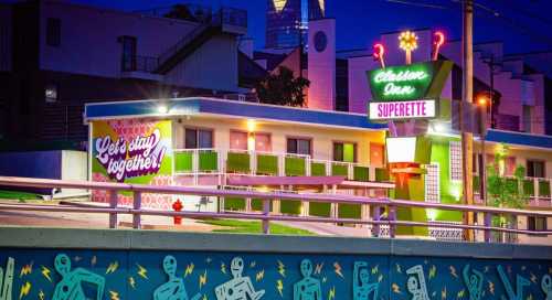 A colorful motel at night with a neon sign, featuring the text "Let's stay together!" and vibrant street art below.