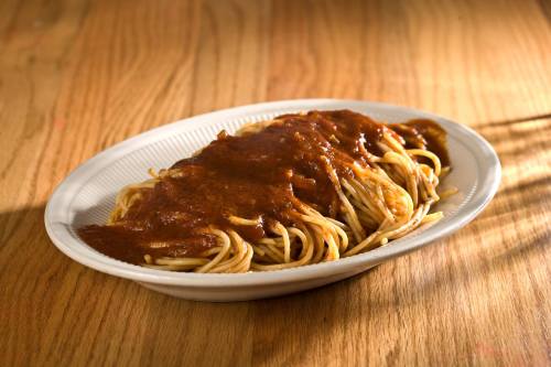 A plate of spaghetti topped with a rich, dark sauce, served on a wooden table.