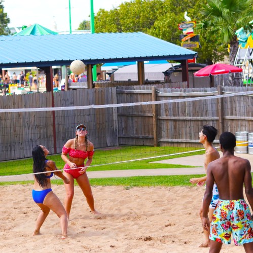 A beach volleyball game in progress with players enjoying a sunny day at a recreational area.