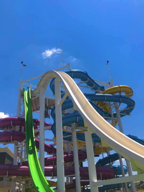 A colorful water slide structure with multiple slides against a clear blue sky.