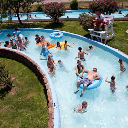 A busy lazy river at a water park with children and adults floating on tubes and enjoying the water.