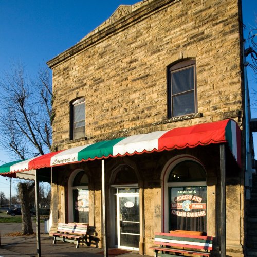 A stone building with a colorful awning, featuring a sign for "Lovera's Grocery and Meat Market."
