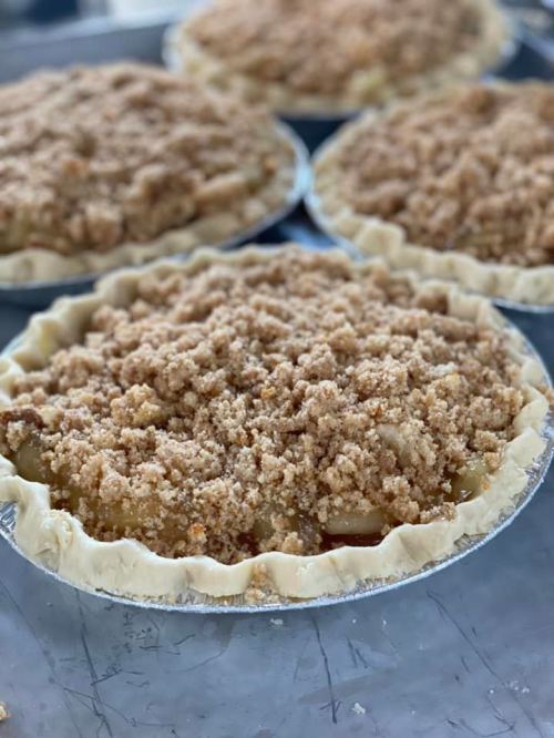Four apple pies with crumb topping, resting on a baking tray.