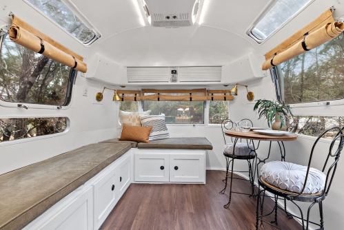 Cozy interior of a modern camper with a seating area, table, and large windows for natural light.
