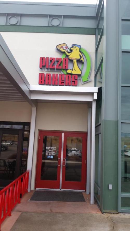 Exterior of Pizza Bakers restaurant with a colorful sign and red double doors.