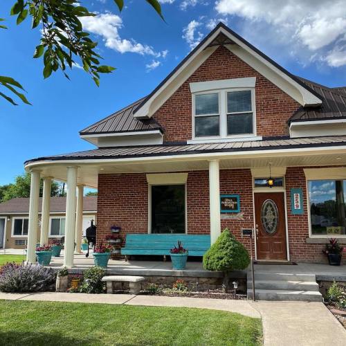 A charming two-story house with a porch, surrounded by greenery and a well-maintained garden.