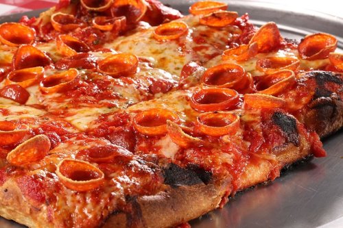 A close-up of a pepperoni pizza with melted cheese and a crispy crust on a metal tray.