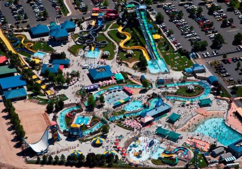 Aerial view of a vibrant water park with slides, pools, and crowds, surrounded by parking and greenery.