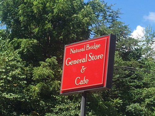 Sign for Natural Bridge General Store & Cafe, surrounded by greenery and blue sky.