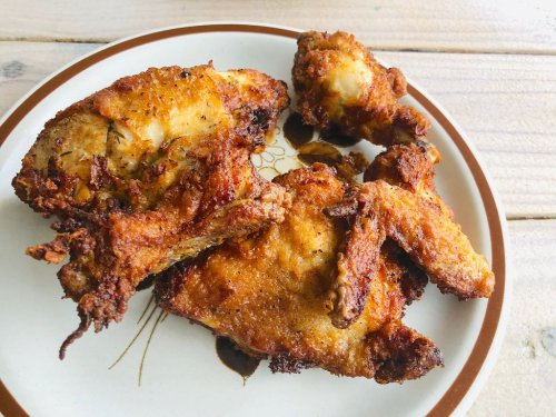 A plate of crispy, golden-brown fried chicken pieces on a wooden surface.