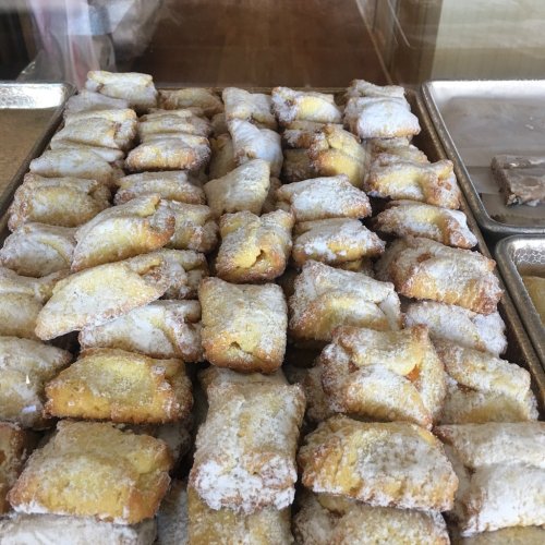 A tray filled with golden, powdered sugar-dusted pastries arranged neatly.