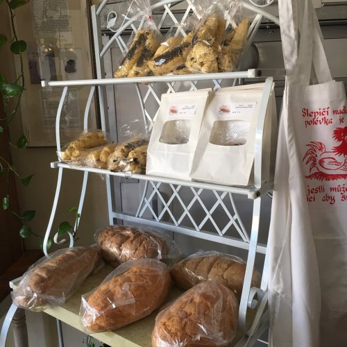 A display shelf with various types of bread and baked goods, including packaged items and a tote bag.