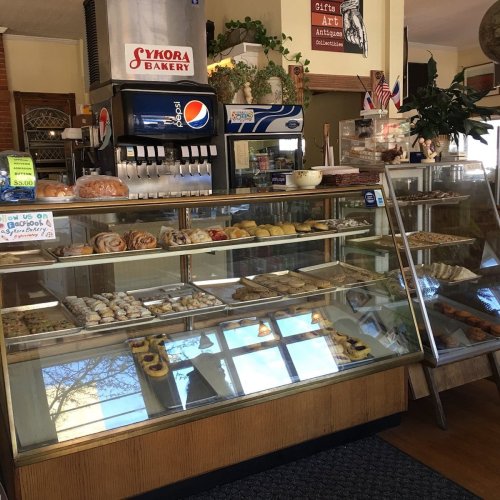 A bakery display case filled with various pastries and desserts, with a soda fountain in the background.